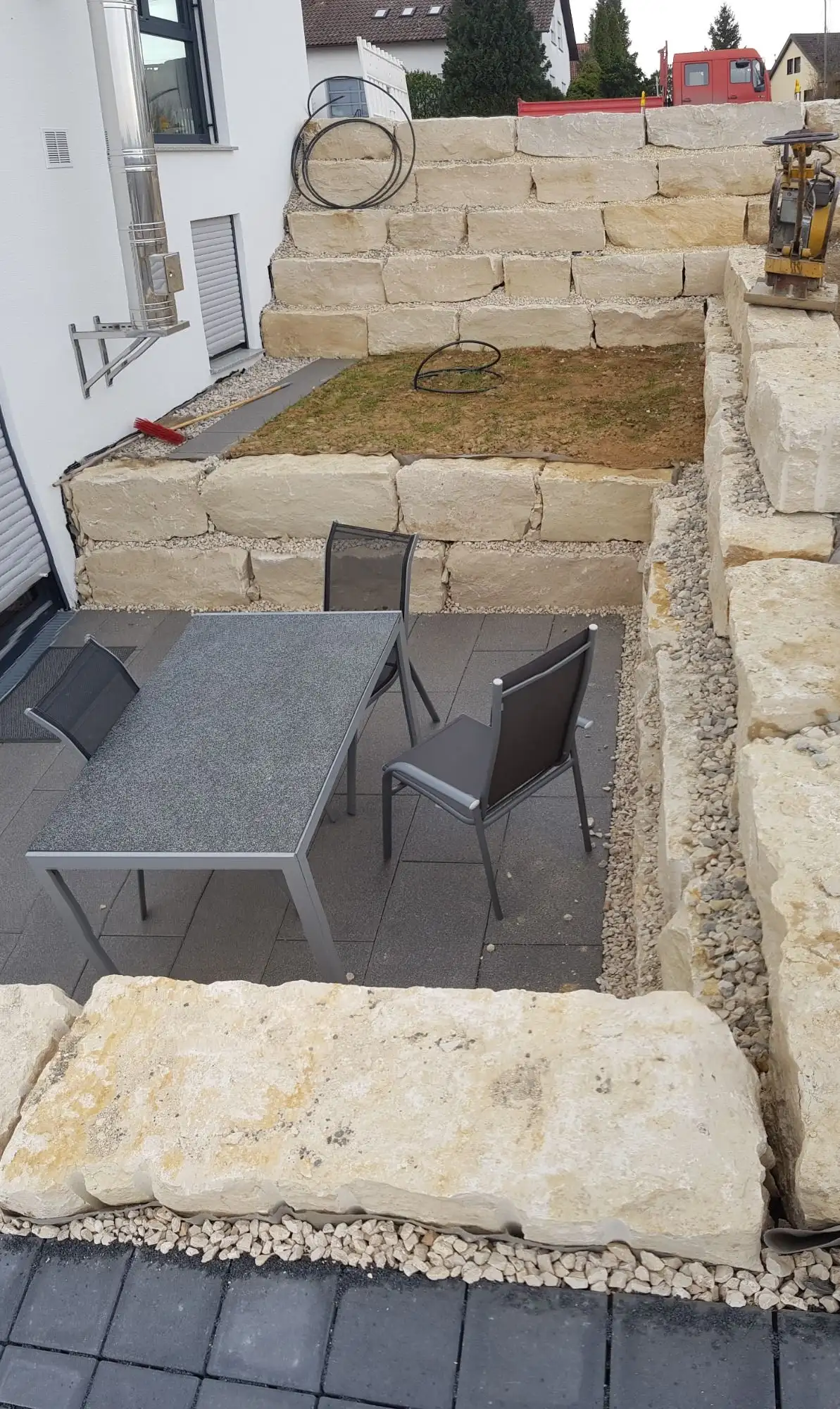 Sitzplatz aus dunklen Platten, eingefasst von hellen Kalkstein-Blockmauern